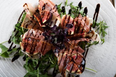 Geleneksel İtalyan salatası incirli jambonlu jambon ya da ince dilimlenmiş jambonlu jambonlu İtalyan salatası İtalyan restoranında beyaz tabakta servis edilir.