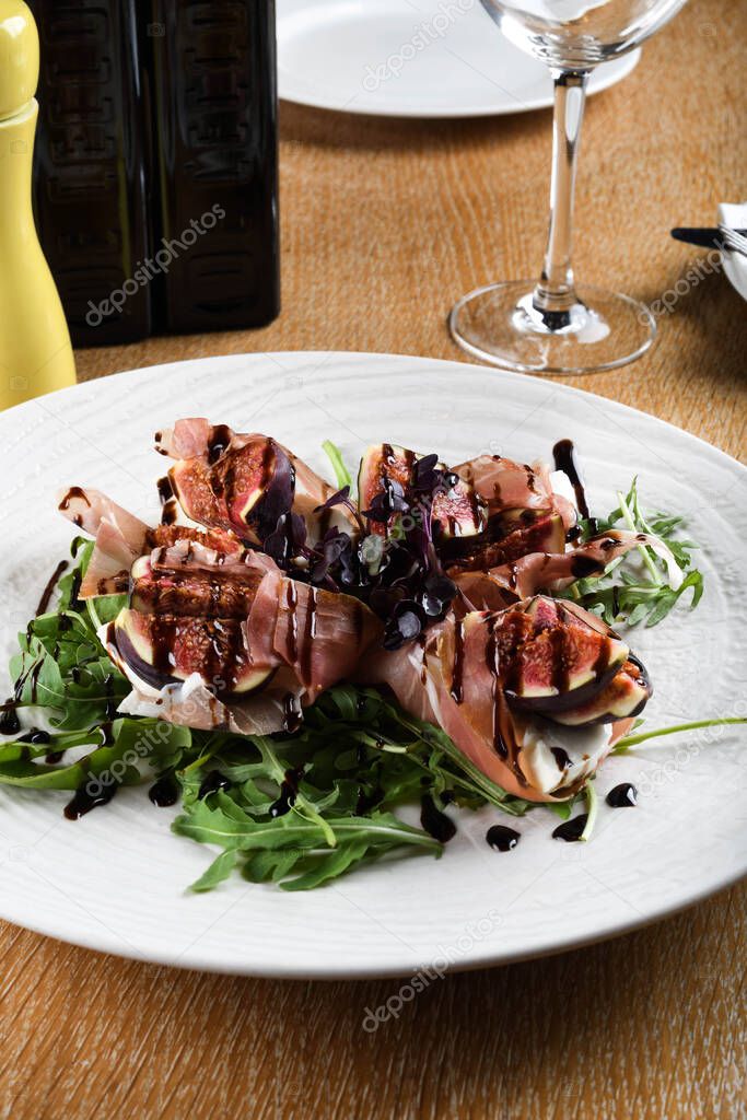 Traditional Italian salad made with figs, Prosciutto dry-cured ham or Parma ham thinly sliced prosciutto crudo served on a white plate in an Italian Restaurant