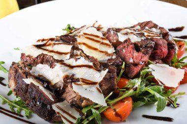 Geleneksel İtalyan ana yemeği. Tagliata bifteği, roka, kiraz domatesleri, Grana Padano talaşı, balzamik redüksiyon. Emilia Romagna bölgesine özgü yiyecekler. Restoran masası kurulumu