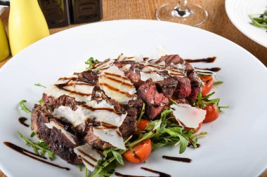 Geleneksel İtalyan ana yemeği. Tagliata bifteği, roka, kiraz domatesleri, Grana Padano talaşı, balzamik redüksiyon. Emilia Romagna bölgesine özgü yiyecekler. Restoran masası kurulumu