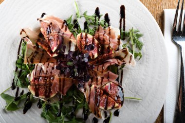 Geleneksel İtalyan salatası incirli jambonlu jambon ya da ince dilimlenmiş jambonlu jambonlu İtalyan salatası İtalyan restoranında beyaz tabakta servis edilir.