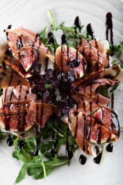Geleneksel İtalyan salatası incirli jambonlu jambon ya da ince dilimlenmiş jambonlu jambonlu İtalyan salatası İtalyan restoranında beyaz tabakta servis edilir.