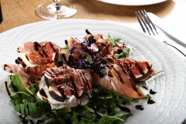 Geleneksel İtalyan salatası incirli jambonlu jambon ya da ince dilimlenmiş jambonlu jambonlu İtalyan salatası İtalyan restoranında beyaz tabakta servis edilir.