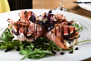 Geleneksel İtalyan salatası incirli jambonlu jambon ya da ince dilimlenmiş jambonlu jambonlu İtalyan salatası İtalyan restoranında beyaz tabakta servis edilir.