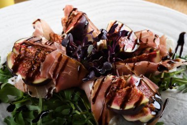 Geleneksel İtalyan salatası incirli jambonlu jambon ya da ince dilimlenmiş jambonlu jambonlu İtalyan salatası İtalyan restoranında beyaz tabakta servis edilir.