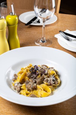 Porcini mantarlı ve mantar kokulu taze pappardelle makarna. İtalyan usulü ve baharatlı geleneksel İtalyan yemeği. Parmesan ve mozzarella peyniri sosu. Restoran masası ayarı.