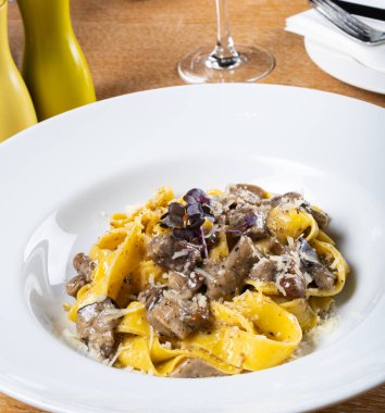 Porcini mantarlı ve mantar kokulu taze pappardelle makarna. İtalyan usulü ve baharatlı geleneksel İtalyan yemeği. Parmesan ve mozzarella peyniri sosu. Restoran masası ayarı.