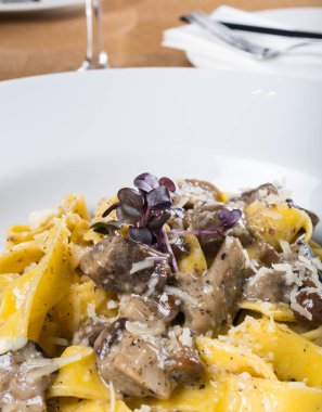 Porcini mantarlı ve mantar kokulu taze pappardelle makarna. İtalyan usulü ve baharatlı geleneksel İtalyan yemeği. Parmesan ve mozzarella peyniri sosu. Restoran masası ayarı.