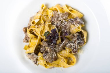 Porcini mantarlı ve mantar kokulu taze pappardelle makarna. İtalyan usulü ve baharatlı geleneksel İtalyan yemeği. Parmesan ve mozzarella peyniri sosu. Restoran masası ayarı.