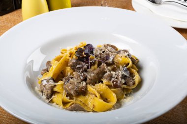 Porcini mantarlı ve mantar kokulu taze pappardelle makarna. İtalyan usulü ve baharatlı geleneksel İtalyan yemeği. Parmesan ve mozzarella peyniri sosu. Restoran masası ayarı.