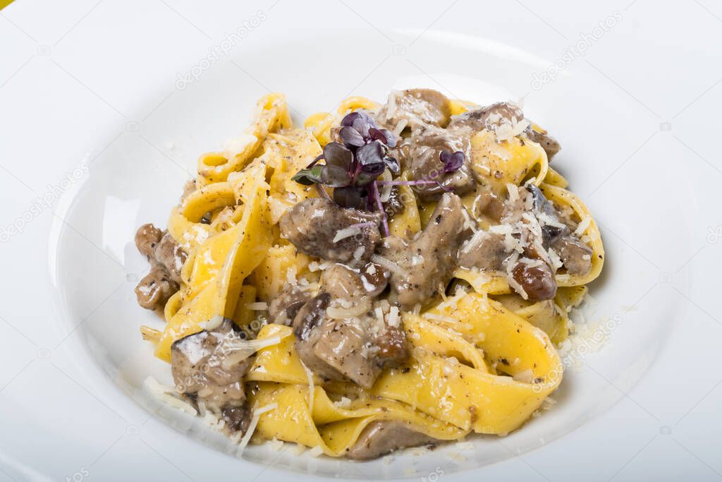 Fresh pappardelle pasta with porcini mushrooms and truffle scent. Traditional italian dish cooked in italian style and spices. Parmesan and mozzarella cheese sauce dressing. Restaurant table setting.
