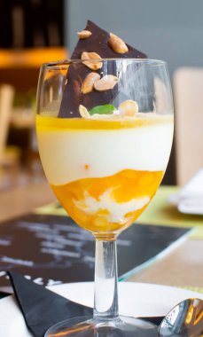 Portakallı İtalyan panna cotta, bir şarap kadehinde servis edilir. Lokantada koyu çikolatalı fıstık ve badem gevreği bulunur.