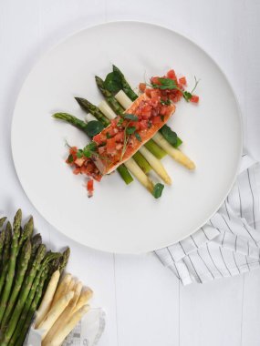 Izgara somon fileto, beyaz ve yeşil kuşkonmaz. Sağlıklı beslenme konsepti. Üstüne doğranmış domates, stüdyo çekimi.