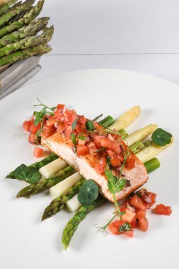 Izgara somon fileto, beyaz ve yeşil kuşkonmaz. Sağlıklı beslenme konsepti. Üstüne doğranmış domates, stüdyo çekimi.