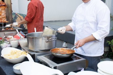 Şef makarna, haşlama ve pişirme hazırlıyor. Yemek şirketi resepsiyon sırasında canlı yemek yapıyor.