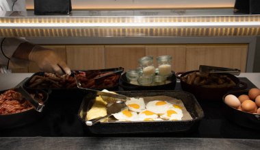Bir otel ya da restoran ortamında yumurta ve omlet istasyonu, yemek servisi ya da açık büfe kahvaltısı ya da mutfak.