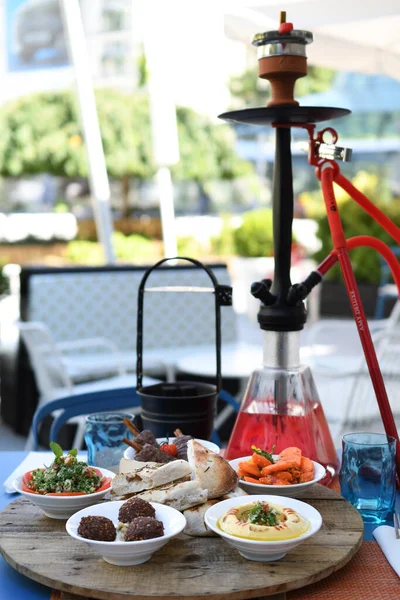 Shisha hookah on restaurant table in the garden. Metal hookah on a summer terrace with a blurred background.