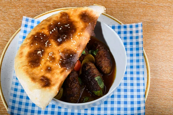 Kebab meat balls in a white bowl, served with a pita bread cover on top. Kebabs consist of cut up or ground meat, sometimes with vegetables, although kebabs are typically cooked on a skewer over a fir