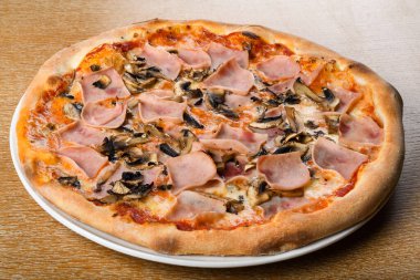 Pizza prosciutto e funghi, geleneksel İtalyan fırını hamur üzerine sos, mozzarella, jambon, mantar. Basit kahverengi ahşap masa restoranı. Yakın çekim ve makro çekim