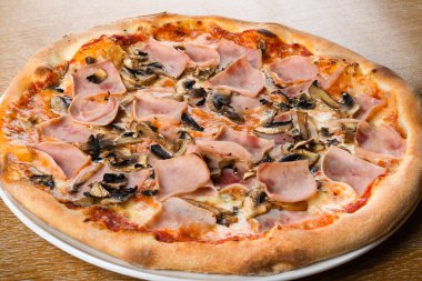 Pizza prosciutto e funghi, geleneksel İtalyan fırını hamur üzerine sos, mozzarella, jambon, mantar. Basit kahverengi ahşap masa restoranı. Yakın çekim ve makro çekim