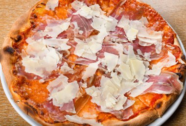 İtalyan pizza fırını geleneksel domates sosu, mozzarella, prosciutto, roka, parmesan talaşı. Basit kahverengi ahşap restoran masası seti. Taze yemek, yemek, yemek.