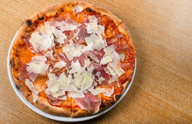 İtalyan pizza fırını geleneksel domates sosu, mozzarella, prosciutto, roka, parmesan talaşı. Basit kahverengi ahşap restoran masası seti. Taze yemek, yemek, yemek.