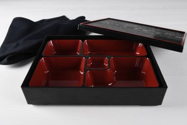 Kırmızı ve siyah boş bento kutusu, öğle yemeği için geleneksel Japon tepsisi suşi, nigiri, sashimi spesiyaliteleri dahil.