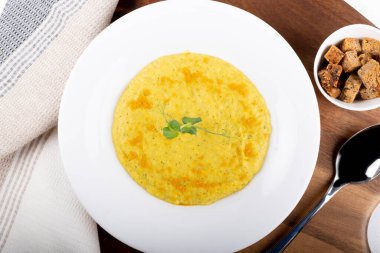 Beyaz bir kasede karışık sebze kremalı çorba, beyaz arka planda izole edilmiş, ahşap mutfak kesme tahtası, peçete, kızarmış ekmekle servis ediliyor. Yukarıdaki biçimi göster ve kapat, temiz ve basit arkaplan