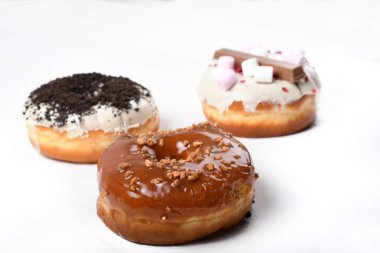 Üç erimiş çikolata, lokum, bisküvi parçacıkları, beyaz tahta üzerinde karamel şekerli çörekler.