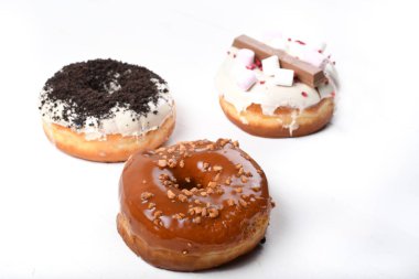 Üç erimiş çikolata, lokum, bisküvi parçacıkları, beyaz tahta üzerinde karamel şekerli çörekler.