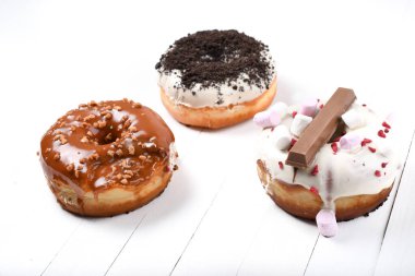 Üç erimiş çikolata, lokum, bisküvi parçacıkları, beyaz tahta üzerinde karamel şekerli çörekler.