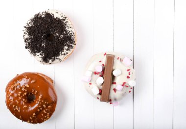 Üç erimiş çikolata, lokum, bisküvi parçacıkları, beyaz tahta üzerinde karamel şekerli çörekler.