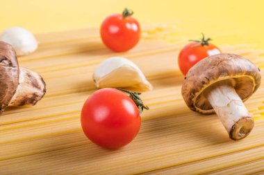 Sarı arka planda makarna pişirmek için malzemeli spagetti makarna. Renkli üst ve İtalyan yemeği için ham malzemelerin yakın çekim görüntüsü. Terfi için fotokopi alanı olan düz dizayn kavramı