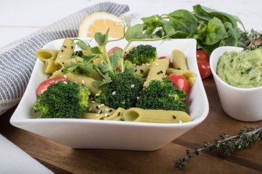 Tahtada izole edilmiş yeşil bezelyelerden yapılmış glütensiz pişmiş makarna. Fesleğen, domates, avokado ve kişniş. Yukarıdan ateş edilmiş ve yakın plan. yemek arkaplanı İtalyan makarna