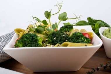 Tahtada izole edilmiş yeşil bezelyelerden yapılmış glütensiz pişmiş makarna. Fesleğen, domates, avokado ve kişniş. Yukarıdan ateş edilmiş ve yakın plan. yemek arkaplanı İtalyan makarna