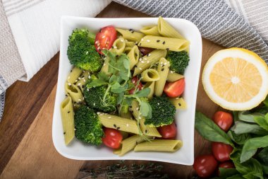 Tahtada izole edilmiş yeşil bezelyelerden yapılmış glütensiz pişmiş makarna. Fesleğen, domates, avokado ve kişniş. Yukarıdan ateş edilmiş ve yakın plan. yemek arkaplanı İtalyan makarna