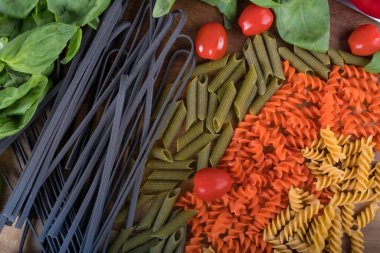 Nohuttan glütensiz makarna, kırmızı mercimek, tahta kesme tahtasındaki bezelye çeşitleri. Fesleğen, domates ve sarımsak. Yukarıdan ve yakından çekilmiş. Yemek arkaplanı İtalyan Penne.