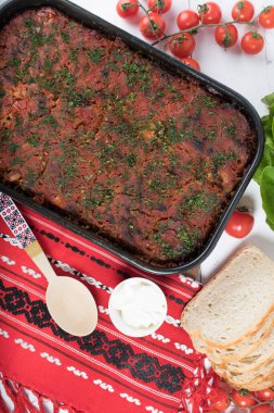 Lahana, domates ezmesi ve kıyma, pirinç ve dereotu, kırmızı peçete, salata ve domates, ekmek ve baharattan yapılan geleneksel Romen yemeği