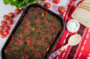 Lahana, domates ezmesi ve kıyma, pirinç ve dereotu, kırmızı peçete, salata ve domates, ekmek ve baharattan yapılan geleneksel Romen yemeği