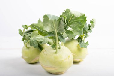 Üç parça kohlrabi sebzesi, basit sarı arkaplanda, kopyalama alanı ile izole edilmiş. Lahana ve turp familyasından yeşil yapraklı sebzeler, bahçede yetişen biyolojik ve organik bitkiler.