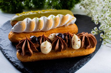 Krema ve sosla doldurulmuş choux hamur hamurundan yapılmış ekler. Zarif, lüks, pahalı şekerleme konsepti. Taze Yemek Büfesi Yemek Yemeği Paylaşım Partisi Konsepti