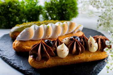 Krema ve sosla doldurulmuş choux hamur hamurundan yapılmış ekler. Zarif, lüks, pahalı şekerleme konsepti. Taze Yemek Büfesi Yemek Yemeği Paylaşım Partisi Konsepti