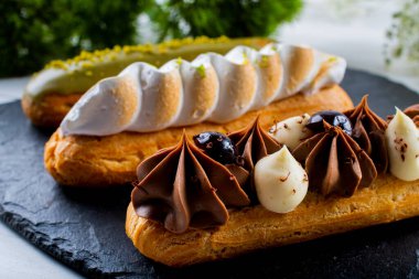 Krema ve sosla doldurulmuş choux hamur hamurundan yapılmış ekler. Zarif, lüks, pahalı şekerleme konsepti. Taze Yemek Büfesi Yemek Yemeği Paylaşım Partisi Konsepti