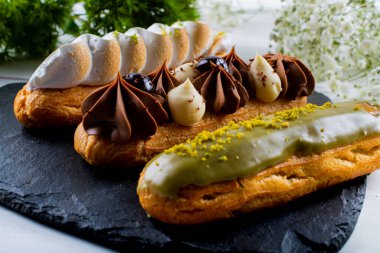 Krema ve sosla doldurulmuş choux hamur hamurundan yapılmış ekler. Zarif, lüks, pahalı şekerleme konsepti. Taze Yemek Büfesi Yemek Yemeği Paylaşım Partisi Konsepti