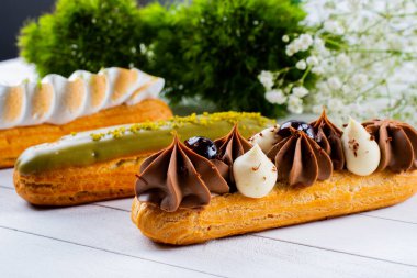 Krema ve sosla doldurulmuş choux hamur hamurundan yapılmış ekler. Zarif, lüks, pahalı şekerleme konsepti. Taze Yemek Büfesi Yemek Yemeği Paylaşım Partisi Konsepti