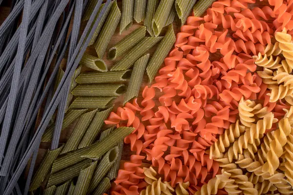 ひよこ豆 赤レンズ豆 木製のまな板上のエンドウ豆からグルテンフリーペンネパスタの異なるタイプの盛り合わせ バジルとトマトとニンニク 上から撮影して閉じます 料理の背景イタリアのペンネ — ストック写真