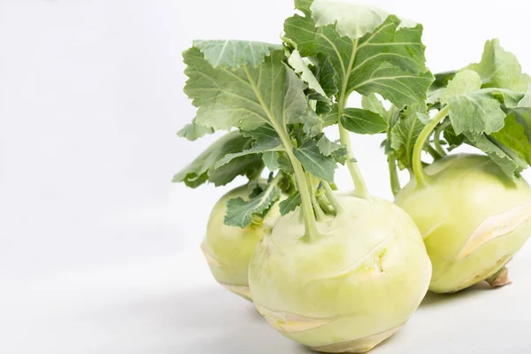 Three pieces of kohlrabi vegetable isolated on yellow simple background with copy space. Green leafy vegetable from cabbage and radish family, bio and organic grown from the garden