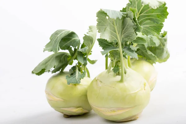 Three pieces of kohlrabi vegetable isolated on yellow simple background with copy space. Green leafy vegetable from cabbage and radish family, bio and organic grown from the garden