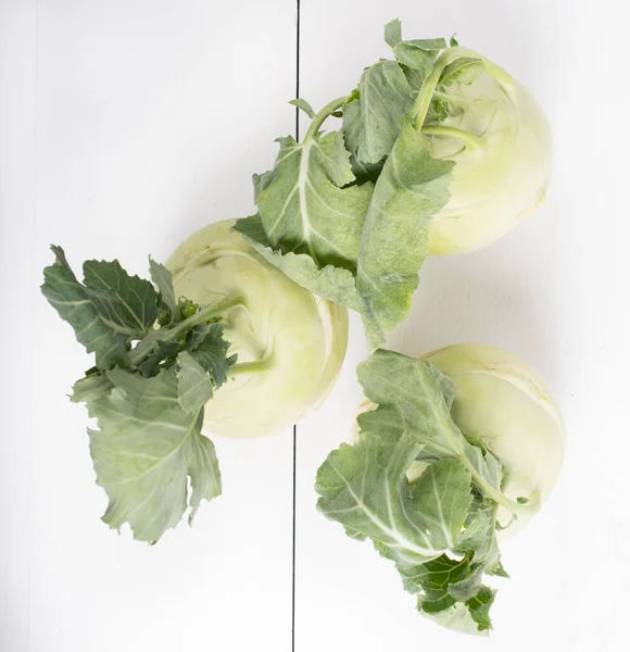 Three pieces of kohlrabi vegetable isolated on yellow simple background with copy space. Green leafy vegetable from cabbage and radish family, bio and organic grown from the garden