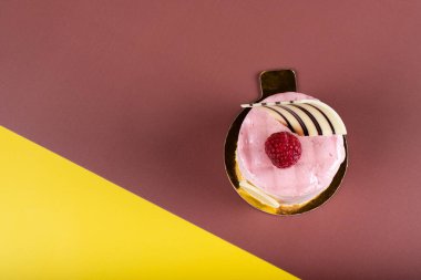 Ahududu vanilyalı ve beyaz çikolatalı mus tatlısı. Logo alanı sarı ve kahverengi. Minimalist kavramsal tasarım, metin kopyalamak için boş alan, basit renkli kağıt arkaplan